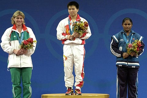 (From L-R) Erzebet Markus from Hungary, Weining Lin from China and Karnam Malleswari from India stand on the podium after winning the women's -69kg weightlifting final. (Photo | AFP)