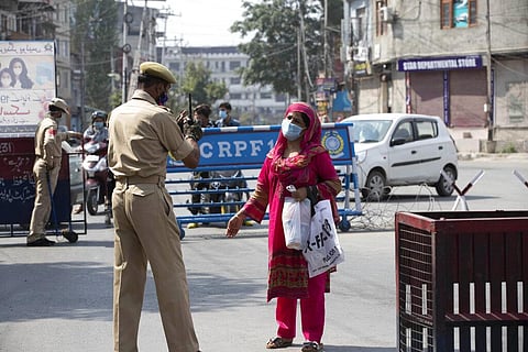 A Kashmiri woman requests a police officer to let her cross a street during curfew in Srinagar, Tuesday, August 4, 2020. (Photo | AP)