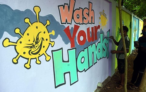 Artists busy completing a wall painting over theme of Covid-19. (Photo | Biswanath Swain, EPS)