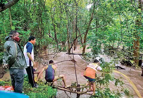 Fire and safety department staff rescuing forest staff from flood water in Velugodu on Saturday I Express