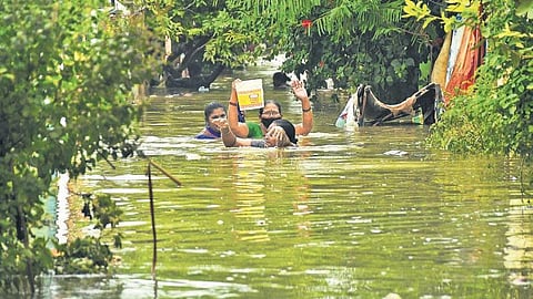 People wade through waist-deep water at Tarakarama Nagar in Vijayawada on Tuesday | Prasant Madugula