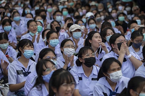 High school students claps and blow whistles during a protest rally in Bangkok, Thailand