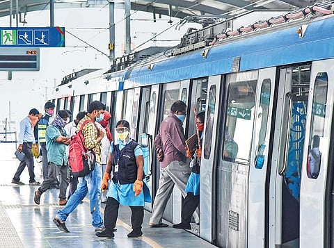 Metro passengers maintain social distancing norms while getting on a train at one of the stations
