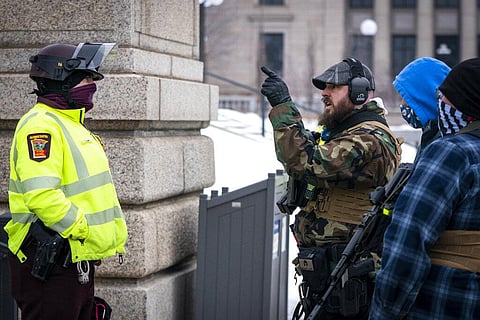 A man speaks with a Minnesota State trooper during a rally supporting President Trump at the Minnesota Capitol. (Photo | AP)