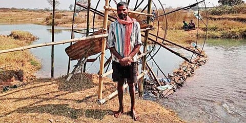 Mahur Tipiria stands near his innovative waterwheel in Mayurbhanj’s Sukruli. (Photo | EPS)