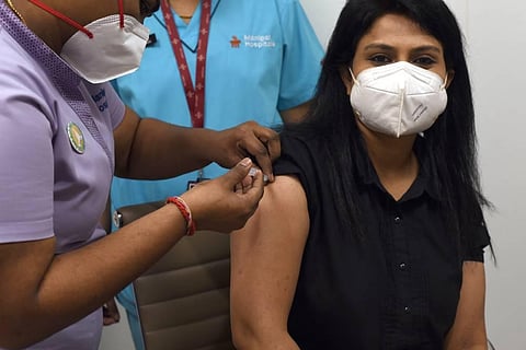 Health minister K Sudhakar watches over a health worker taking while she takes the jab at Manipal Hospital on Sunday in Bengaluru. (Photo | Nagaraja Gadekal P/EPS)