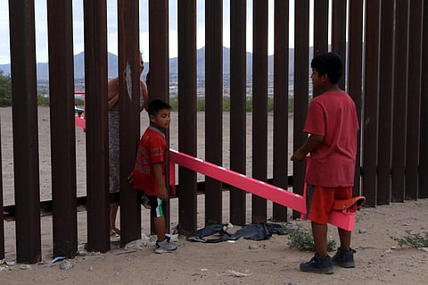 American and Mexican families play with a toy called 'up and down' (Seesaw swing) over the Mexican border. (Photo| AFP)