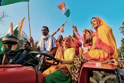 Farmers hold the Tricolor as they ride on a tractor during their protest against Centre's farm reform laws. (Photo| PTI)