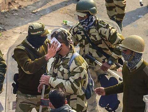 An injured security person receives help from colleagues during clashes with farmers after their tractor rally turned violent, in New Delhi. (Photo | PTI)
