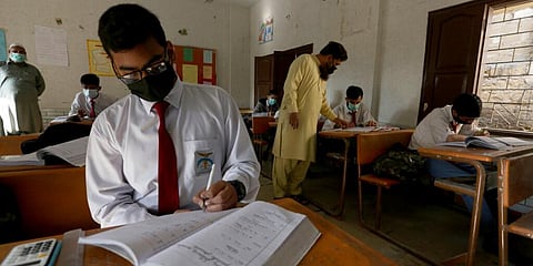 Students wearing face masks to prevent the spread of the coronavirus attend a class at their school, in Karachi. (Photo | AP)