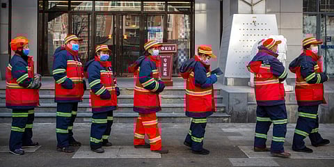 Urban street cleaners wearing face masks to protect against the spread of the coronavirus line up for mass COVID-19 testing in a central district of Beijing. (Photo | AP)