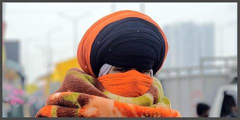 A farmer wraps a blanket to beat cold after rain during their ongoing protest against the three farm laws at Gazipur border, in Delhi. (Photo | ANI)