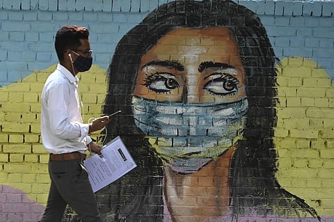 A man walks past a mural depicting the Covid-19 coronavirus. (Photo| AFP)