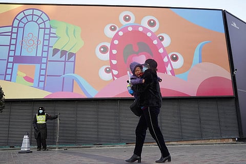 A woman carries a crying child past decorations at an empty mall during a cold and windy day in Beijing on Wednesday, Jan. 6, 2021. (Photo | AP)