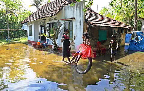A mother orders her daugther to get down from the tyre hung on a tree near the waterlogged area to prevent her from falling  in the pool of water. (Photo| Albin Mathew, EPS)