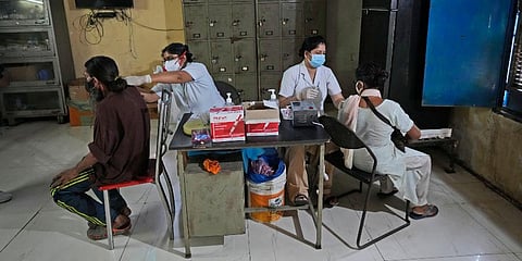 Health workers inoculate people against COVID-19 during a special vaccination drive at a night shelter in New Delhi. (Photo | AP)