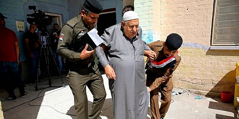 Police officers help an elderly man during parliamentary elections at a polling station in Basra, Iraq. (Photo | AP)