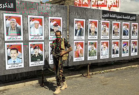 Yemen's Huthi rebel fighter walks past a banner showing victims and commemorating fifth anniversary of a air strike by Saudi-led coalition on a funeral hall in Sanaa on Oct 9, 2021.  (Photo | AFP)