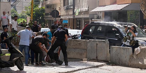 Supporters of a Shiite group allied with Hezbollah help an injured comrade during armed clashes that erupted in the southern Beirut suburb of Dahiyeh, Lebanon, Oct. 14, 2021. (Photo | AP)