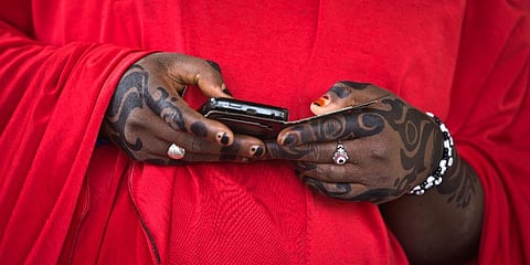 FILE - In this Saturday March 28, 2015, file photo, a woman from the Hausa tribe, looks at her smartphone, at a polling station located in an Islamic school in Daura, Nigeria. (Photo | AP)
