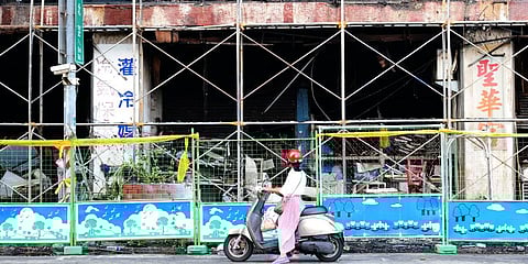 A woman stops to look at the burnt building in Kaohsiung in southern Taiwan. (Photo | AP)