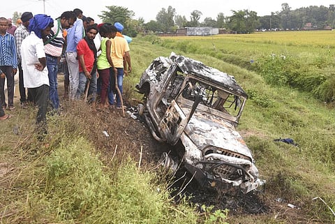 File photo of villagers watching a burnt car before it was run over on farmers at Tikonia village in Lakhimpur Kheri. (Photo | AP)