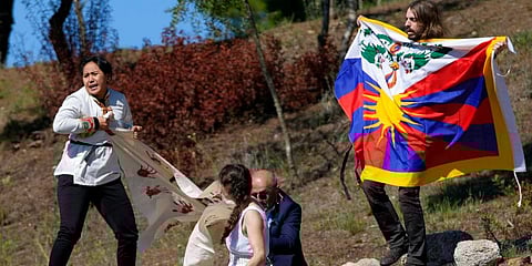 A police officer tries to stop protesters displaying a Tibetan flag and a banner reading 'No genocide games' during the lighting of the Olympic flame at Ancient Olympia site. (Photo | AP)