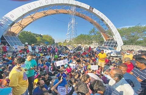 Athletes, children and parents raise slogans against the allocation of 5 acres of land in Gachibowli stadium to TIMS Hospital, in Hyderabad on Friday