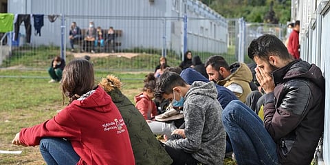 Migrants sit in front of containers at the Central Initial Reception Facility for Asylum Seekers, ZABH, in the German state of Brandenburg in Eisenhuettenstadt, Germany, Oct. 6, 2021. (Photo | AP)