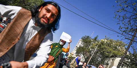 A Taliban member (L) attacks a foreign photographer covering a women's rights protest in Kabul. (Photo| AFP)