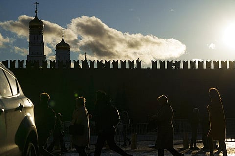 People cross a street after a dovetail-shaped tooth on top of the Kremlin wall was broken, center right, with the Ivan the Great Bell Tower, left (Photo | AP)
