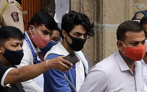 Aryan Khan, center, escorted by law enforcement officials from Narcotics Control Bureau office is being taken for a medical check up, in Mumbai. (File Photo | AP)