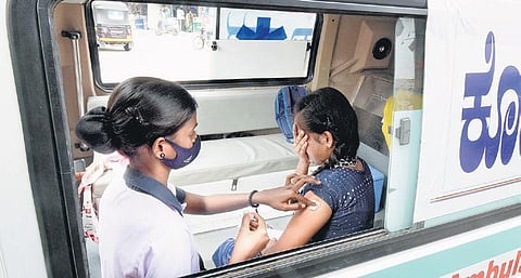 A health worker administers Covid-19 vaccine to a young woman inside a dedicated van in Mysuru on Thursday