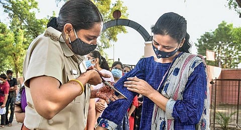 A securitywoman cuts the sleeves of a candidate at an exam centre in Bikaner. (Photo | PTI)