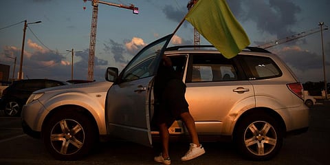 A man places a green flag on his car as he prepares to join a convoy of cars and protest against the Health Ministry's green pass restrictions, in Tel Aviv, Israel. (Photo | AP)
