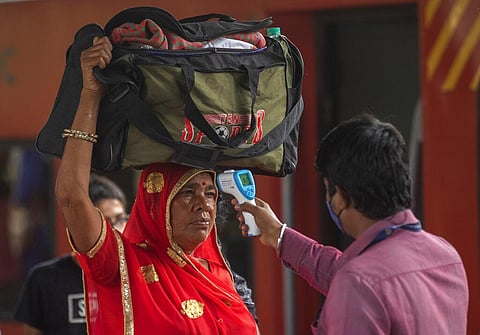 A health worker checks body temperature of a traveler as a precaution against the coronavirus before allowing her to proceed at train station. (Photo | AP)