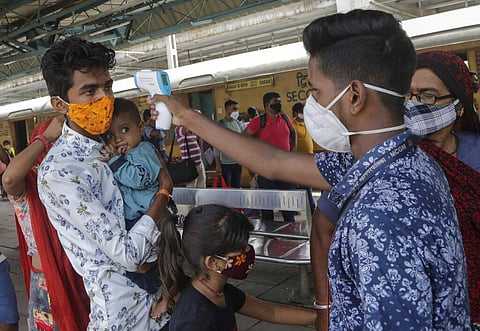 A health worker checks the temperature of a passenger arriving by an outstation train as they screen people to identify those infected with the coronavirus in Mumbai. (Photo | PTI)