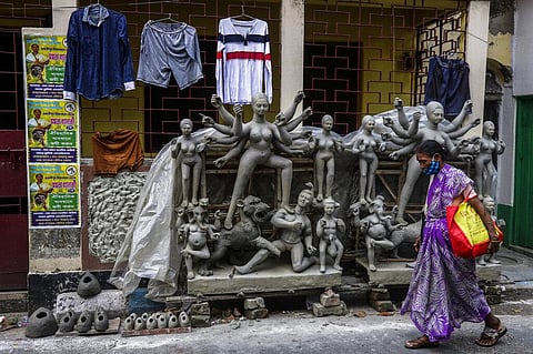 A woman walks past unfinished clay images of Hindu goddess Durga in Kolkata, India, Sunday, Oct. 3, 2021. (Photo | AP)