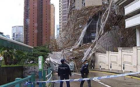 Officials inspect the scene of a section of an apartment building scaffolding that collapsed during heavy weather in Hong Kong. (Photo | AP)