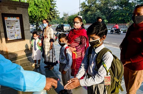 Students being sanitised upon their arrival at the school, in New Delhi. (Photo | PTI)