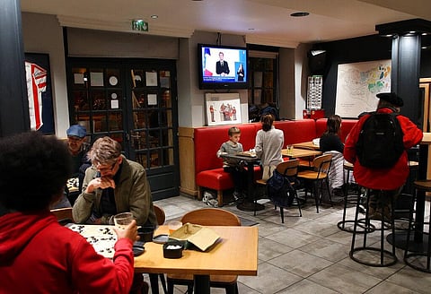 People listen as France's President Emmanuel Macron gives an address on television, Tuesday, Nov.9, 2021, in a bar in Bayonne. (Photo | AP)