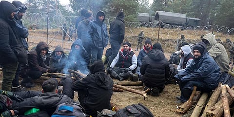 Migrants from the Middle East and elsewhere warm up at the fire gathering at the Belarus-Poland border near Grodno, Belarus. (Photo | AP)