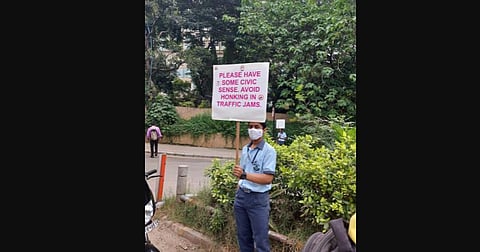 A student holds a placard urging drivers not to honk near the school premises. (Photo | Express)