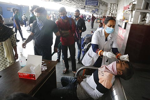 A health worker takes swab samples of a passenger to test for COVID-19, at a railway station in Ahmedabad. (Photo | AP)
