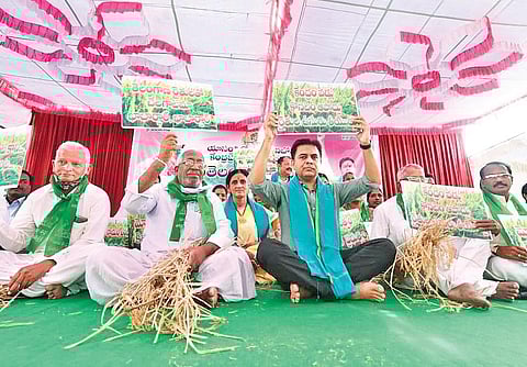 TRS working president KT Rama Rao and party workers hold up placards as they stage a dharna  in Siricilla demanding that the Centre procure paddy produced in Telangana, on Friday