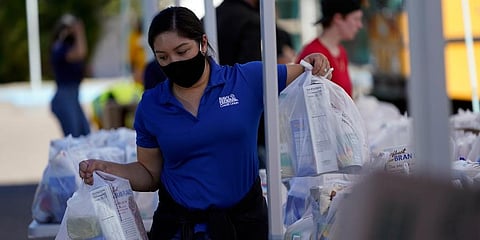 A volunteer loads food into a car at an Armed Services YMCA food distribution in San Diego. (Photo | AP)