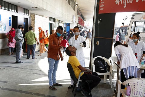 A health worker takes a nasal swab samples of a passenger to test for COVID-19, at a bus stand in Ahmedabad. (Photo | AP)