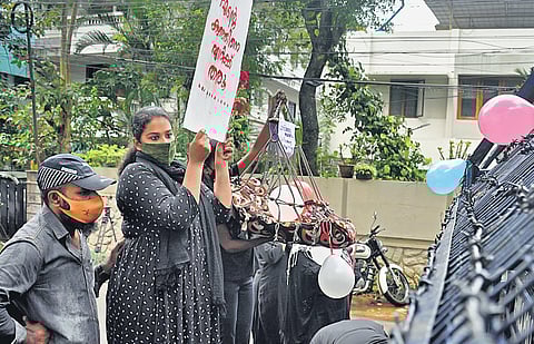 Anupama S Chandran, who has been holding a protest in front of the State Council for Child Welfare office, showing a placard at the Children’s Day rally. One of her supporters is seen holding a cradle