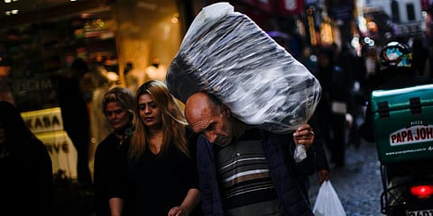 A man carries goods on his back in a commercial area in Istanbul, Turkey. (Photo | AP)