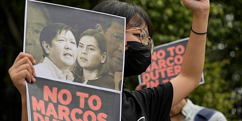 A protester holds a photo bearing the photos of the late dictator's son, Ferdinand Marcos Jr. (L) and Davao city Mayor Sara Duterte during a protest in Quezon city, Philippines. (Photo | AP)
